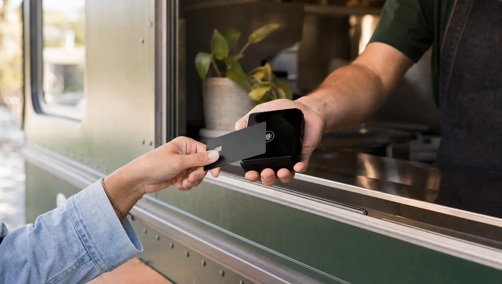 A customer taps a card at a food truck service window on a black SwipeSimple contactless reader.